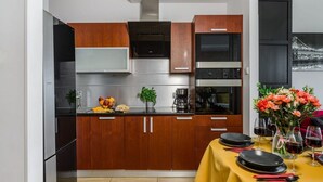 A modern kitchen with wooden cabinets, stainless steel appliances, and a dining area set for a meal. - Warsaw Home with City Views (Warszawa)