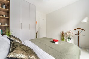 A bedroom with a bed, a wardrobe, a bedside table with a lamp, and a potted plant. - Apartment in Porspoder near Plage du Bourg (Warszawa 2)