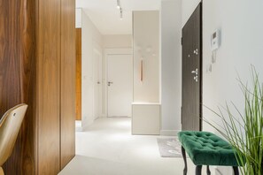 A modern interior with a wooden wardrobe, a green upholstered bench, and a white door leading to another room. - Apartment in Porspoder near Plage du Bourg (Warszawa 2)