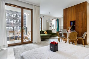 A modern hotel room with a bed, a desk, a laptop, a sofa, and a dining area. - Convenient Base in Warsaw City Centre (Warszawa 2)