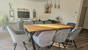A modern dining area with a wooden table and grey upholstered chairs.