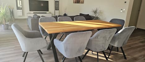 A modern dining area with a wooden table and grey upholstered chairs.