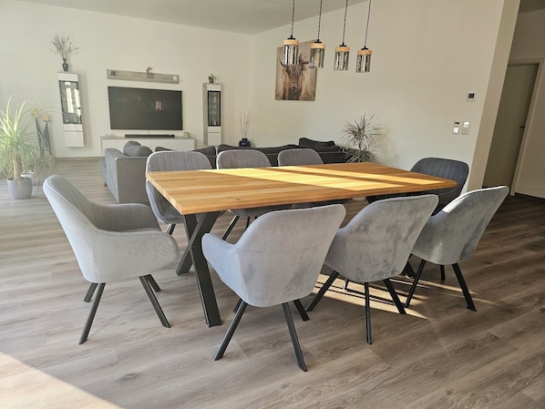 A modern dining area with a wooden table and grey upholstered chairs.