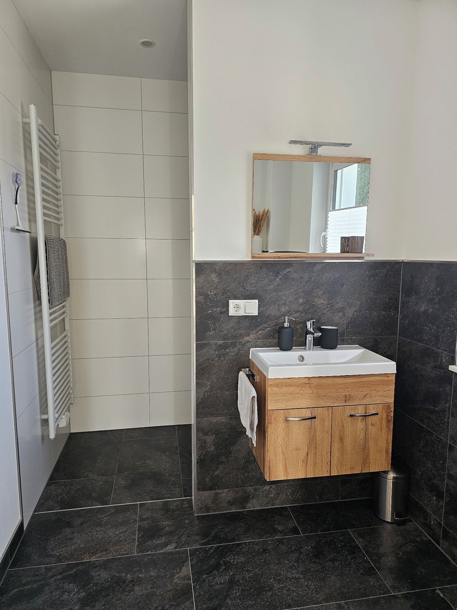 Un bagno moderno con un mobile bagno in legno, uno specchio e una doccia.