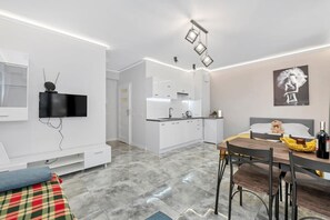 A modern apartment with a dining area, kitchen, and a living space with a TV. - Home near Piotrkowska Street (Łódź)