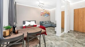 A modern living room with a dining area, grey sofa, and a red throw on the couch. - Quiet Stay near Manufaktura (Łódź)
