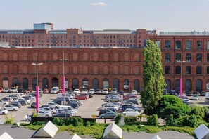 Ein Parkplatz mit mehreren Autos und einem großen Backsteinhaus im Hintergrund.