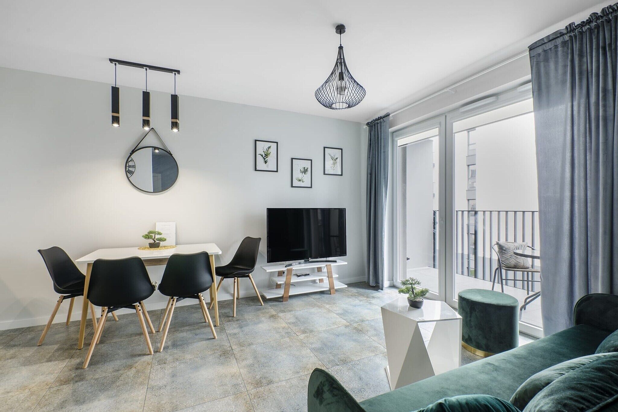 A modern living room with a dining area, a flat-screen TV, and a balcony with a view.