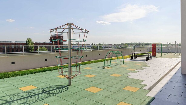 An outdoor playground with a climbing structure, a bench, and a paved area with patterned tiles. - House by Plage de Melon with Garden Retreat (Łódź)