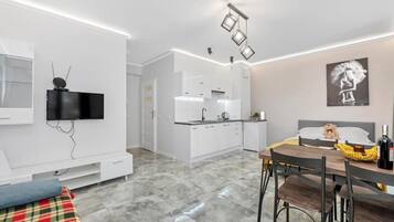 A modern apartment with a dining area, kitchen, and a living space with a TV.