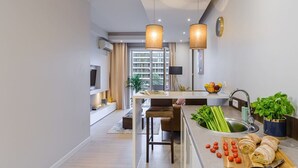 A modern kitchen with a central island, a sink with fresh vegetables, and a dining area with chairs. - Flat on Grzybowska Street (Warszawa)