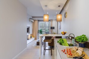 A modern kitchen with a central island, a sink with fresh vegetables, and a dining area with chairs. - Flat on Grzybowska Street (Warszawa)