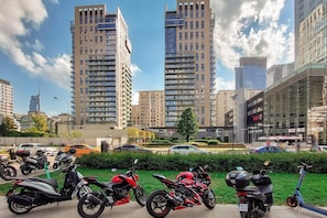 A cityscape with modern high-rise buildings, a parking area with motorcycles, and a clear sky. - Flat on Grzybowska Street (Warszawa)
