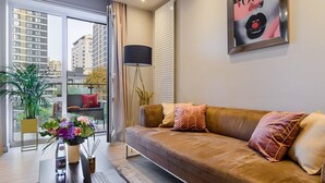 A modern living room with a sofa, a coffee table with a laptop, a floor lamp, and a large window with a view of buildings. - Flat on Grzybowska Street (Warszawa)