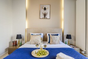 A hotel room with a large bed, two bedside tables, a nightstand, a framed artwork on the wall, and a blue blanket on the bed. - Flat on Grzybowska Street (Warszawa)