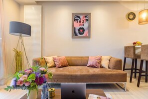 A modern living room with a sofa, a coffee table, a laptop, and a decorative vase with flowers. - Flat on Grzybowska Street (Warszawa)
