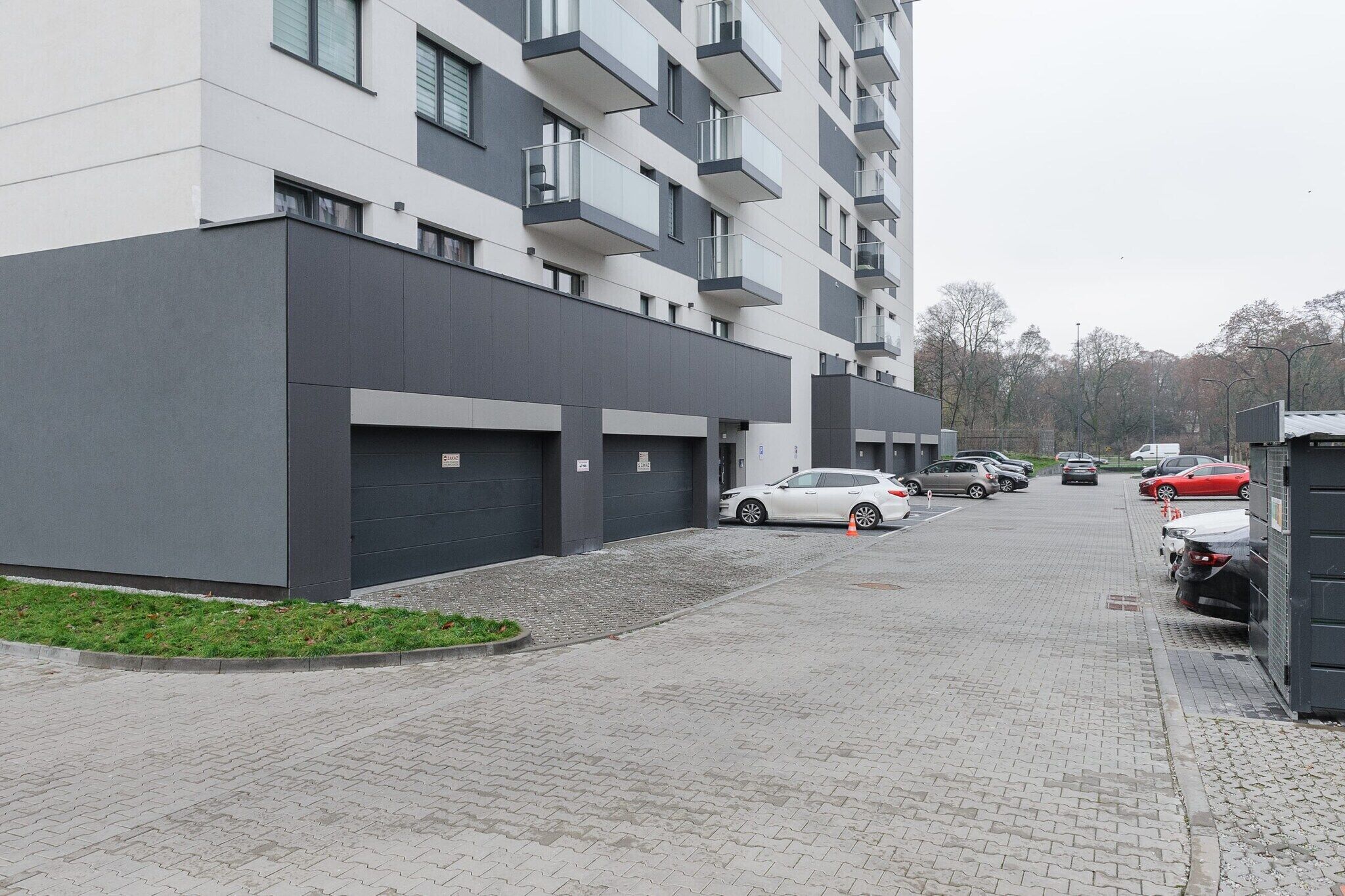 Un edifici residencial de diverses plantes amb zona d'aparcament.