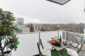 En balkong med ett bord dukat för en måltid, en stol och en krukväxt.
