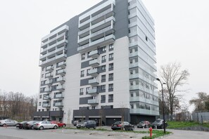 A multi-story residential building with balconies, parking spaces, and a street view. - City Haven near Atlas Arena (Łódź)