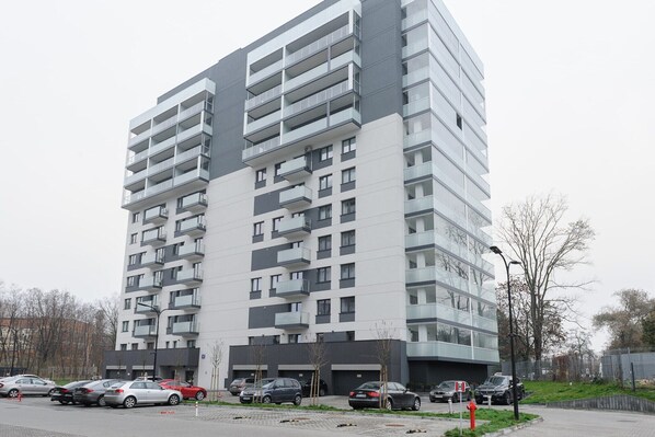 En flervåningsbyggnad med bostäder, balkonger, parkeringsplatser och utsikt över gatan.