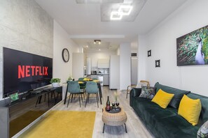 A modern living room with a flat-screen TV, a dining area, and a kitchen in the background. - City Haven near Atlas Arena (Łódź)