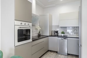 A modern kitchen with a built-in oven, a dishwasher, and a coffee maker. - City Haven near Atlas Arena (Łódź)