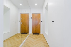 A hallway with two wooden doors, white walls, and a wooden floor. - Charming Apartment near the beach (Warszawa 2)