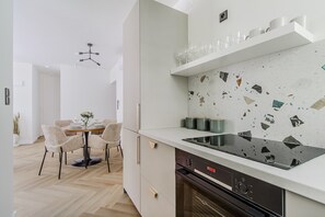Ett modernt kök med en svart bänkskiva, ett stänkskydd med mosaik och en matplats med bord och stolar.