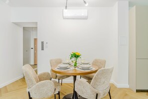 A dining area with a round table, six chairs, and a vase with flowers. - Premium Warsaw City Apartment with Balcony (Warszawa 2)