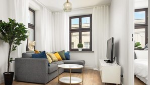 A modern living room with a grey sofa, a round coffee table, a TV, and a potted plant. - Flat near Piotrkowska Street (Łódź)