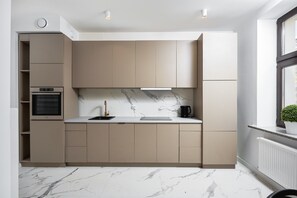 Eine moderne Küche mit integrierten Geräten, einer Marmor-Spritzschutzwand und einem Fenster mit Ausblick.