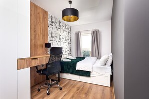 A compact room with a bed, a desk, and a chair. - City View Apartment in Łódź for 6 Guests (Łódź)