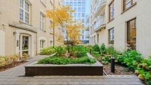 A residential building with a paved walkway, a small garden area with plants, and a tree with yellow leaves. - Siedmiogrodzka Flat with Views (Warszawa)