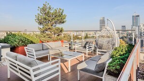 A rooftop terrace with outdoor furniture, a decorative spherical structure, and a view of the city skyline. - Siedmiogrodzka Flat with Views (Warszawa)