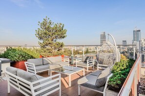Eine Dachterrasse mit Gartenmöbeln, einer dekorativen Kugelform und Blick auf die Stadtlandschaft.