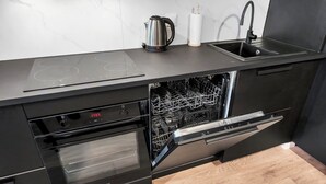 A modern kitchen with integrated appliances, including a dishwasher and oven, and a sink with a faucet. - Elegant Apartment near Vitsula River (Łódź)