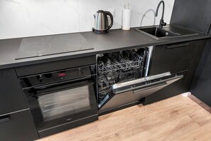 A modern kitchen with integrated appliances, including a dishwasher and oven, and a sink with a faucet. - Elegant Apartment near Vitsula River (Łódź)