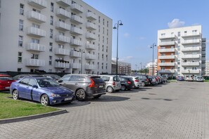A parking lot with multiple cars parked in front of a modern apartment building. - Elegant Apartment near Central Museum of Textiles (Łódź)