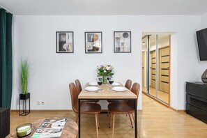 A dining area with a table set for four, surrounded by chairs, with a vase of flowers and wine glasses on the table. - House in Brélès near Rock Beach & Amusement Park (Warszawa 2)