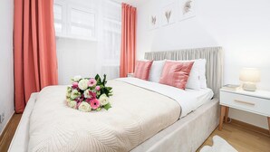 Une chambre à coucher avec un lit, une table de chevet, une lampe et une fenêtre avec des rideaux.