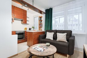 A compact living space with a kitchenette, a sofa, a coffee table, and a bookshelf. - House in Brélès near Rock Beach & Amusement Park (Warszawa 2)
