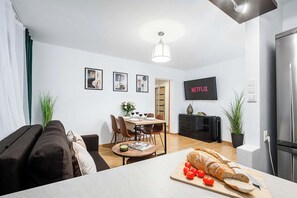 A modern living room with a sofa, dining table, and a kitchen area with a refrigerator. - Central Warsaw Apartment for 5 (Warszawa 2)