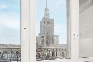 Blick auf ein hohes Gebäude mit einem Uhrenturm durch ein Fenster mit weißem Rahmen.