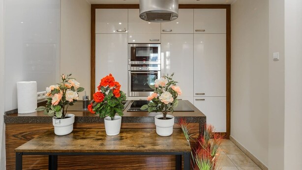 A modern kitchen with white cabinets, a stainless steel oven, and a wooden countertop. - Flat near Metro, Warsaw (Warszawa)