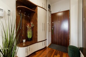 Ein Flur mit Holzausbau, einem Topfpflanzen, einer Tür mit Griff und einer grünen Bank.