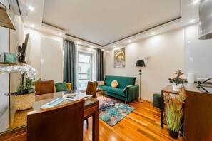 Ein modernes Wohnzimmer mit einem grünen Sofa, einem Holztisch und einem Essbereich mit Stühlen und einem Tisch.