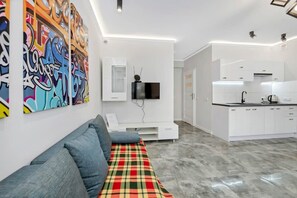 Ein modernes Wohnzimmer mit einer Couch, einem Flachbildfernseher und farbenfroher Graffiti-Kunst an der Wand.