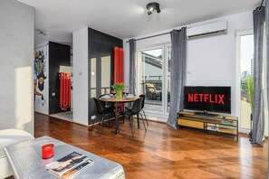Ein modernes Wohnzimmer mit Essbereich, einem Flachbildfernseher und Blick auf die Stadt.