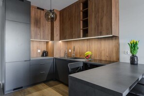 Eine moderne Küche mit Holzschränken, einer schwarzen Arbeitsplatte und einer Pendelleuchte.