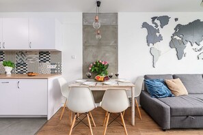 A modern kitchen with white cabinets, a patterned backsplash, and a dining area with a table set for four. - Sunlit Home with City Views (Warszawa)